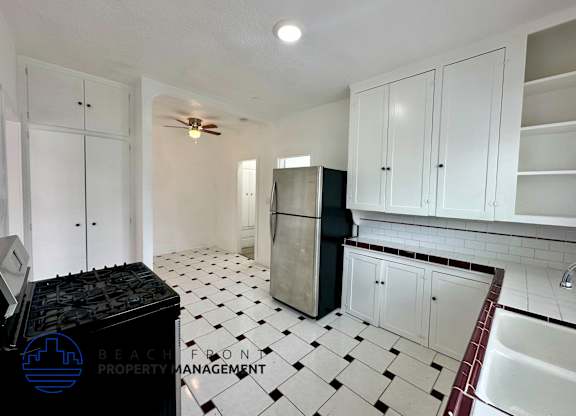 A kitchen with white cabinets and a black fridge.