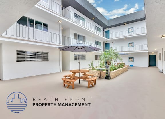 A courtyard with a table and chairs and a tree in the middle.
