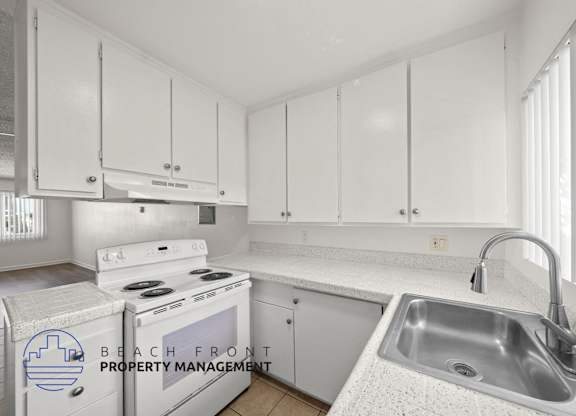 A kitchen with white cabinets and a stove top oven.