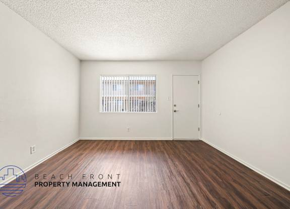 A room with wooden floors and a window with blinds.