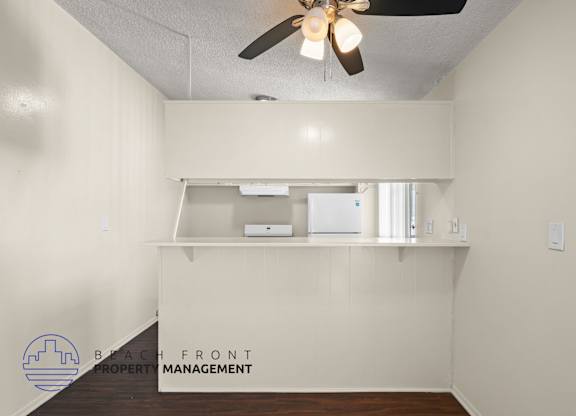 A room with a ceiling fan and a logo for Beach Front Property Management.