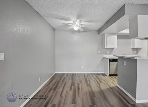 A kitchen area with a fan on the ceiling and wooden flooring.