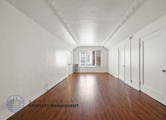 A long hallway with wooden floors and white walls.
