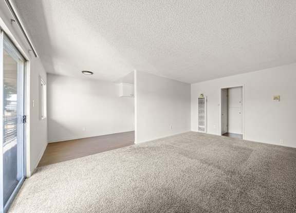 A spacious room with a carpeted floor and white walls.