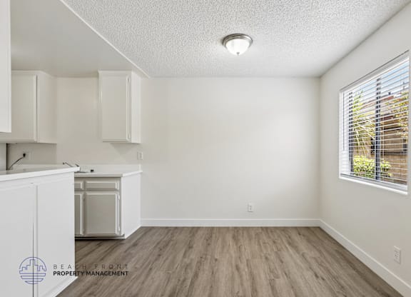 A kitchen with white cabinets and a wooden floor.