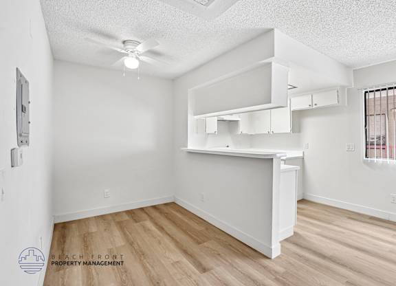 A white room with a ceiling fan and wooden flooring.