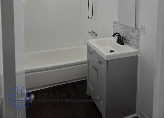 A white bathroom with a sink, mirror, and shower.