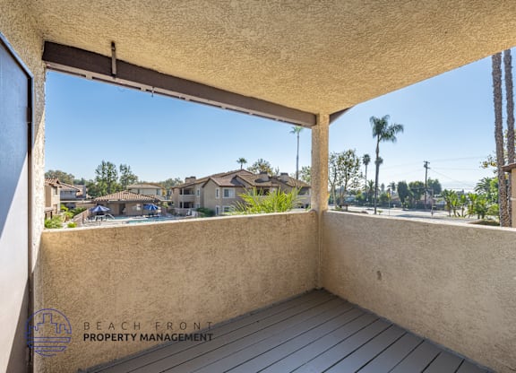 A balcony with a view of a residential area and palm trees.