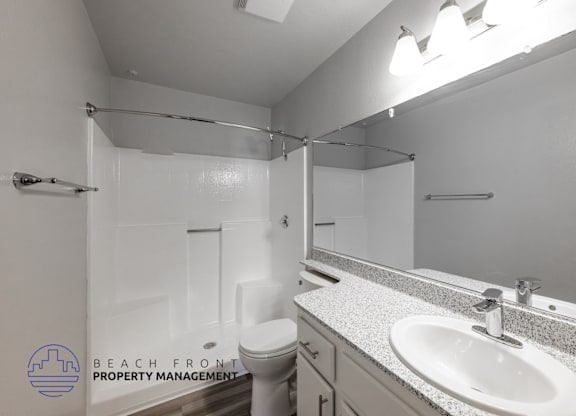 A bathroom with a toilet, sink, and mirror.