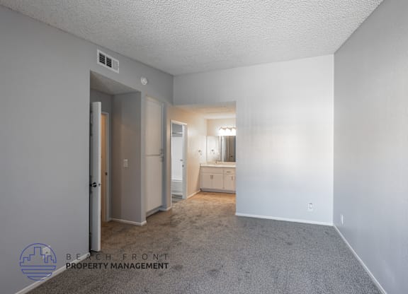 A spacious room with a carpeted floor and a window with blinds.