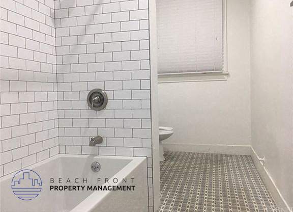a white tiled bathroom with a shower and a toilet