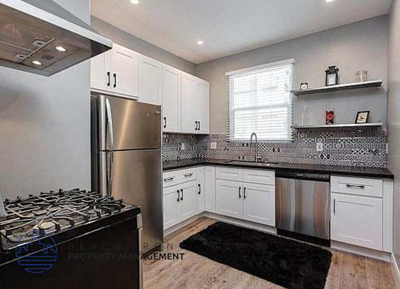 a kitchen with white cabinets and a stainless steel refrigerator