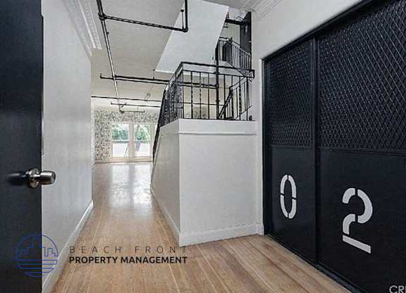 a hallway with two black doors and a staircase