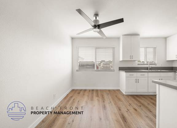 A kitchen with a fan and wooden floors.