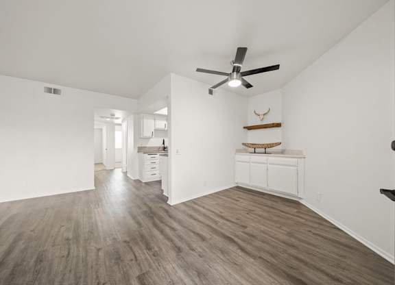 A room with a ceiling fan and wood flooring.