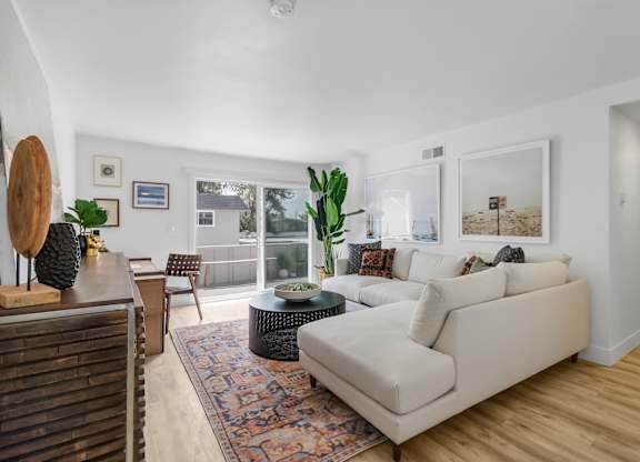 A living room with a white couch and a rug.