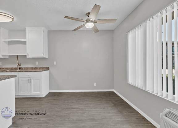 A room with a ceiling fan and a window with blinds.