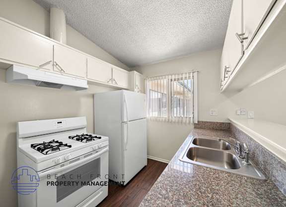 A kitchen with a stove, refrigerator, and sink.