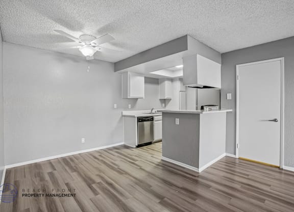 A kitchen area with a refrigerator, oven, and cabinets.