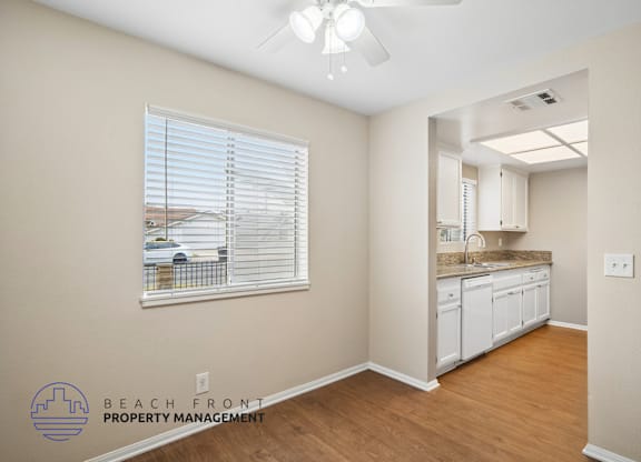 A room with a window showing a view of a beach and a logo for Beach Front Property Management.