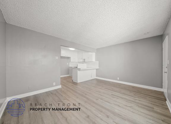 A room with wooden flooring and a logo for Beach Front Property Management.