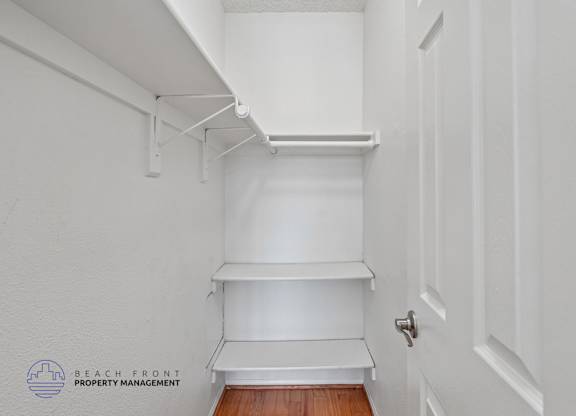 A white hallway with a door and a shelf.