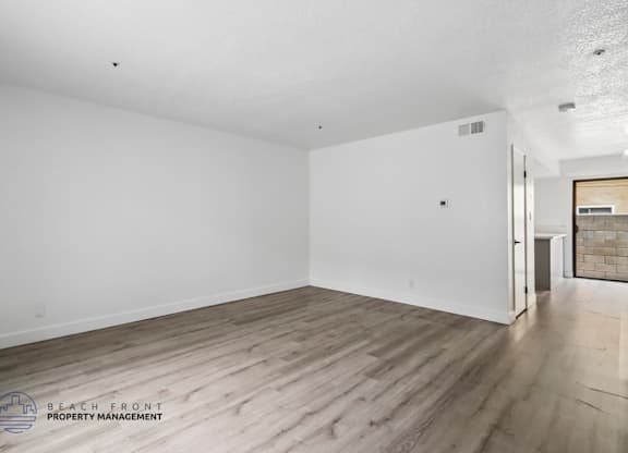 A room with wooden flooring and white walls.