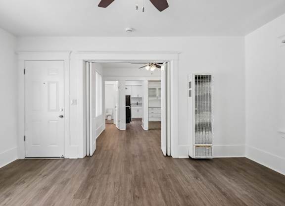 A room with a white door and a ceiling fan.