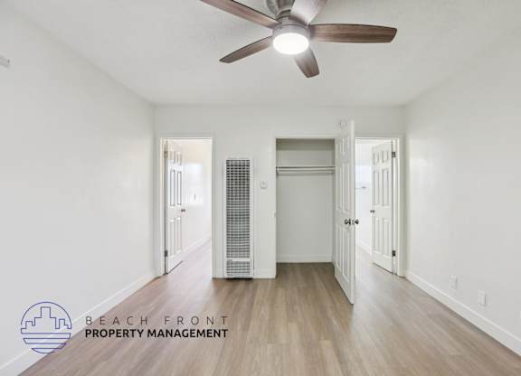 A spacious room with a ceiling fan and a wooden floor.