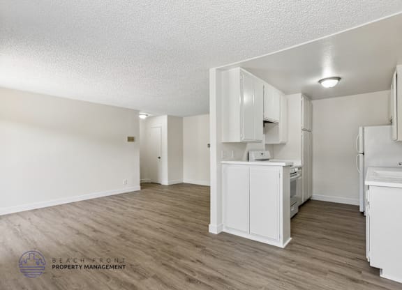 A kitchen with white cabinets and a wooden floor.