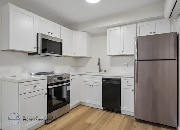 A kitchen with white cabinets and a stainless steel refrigerator.