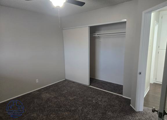A room with a carpeted floor and a ceiling fan.
