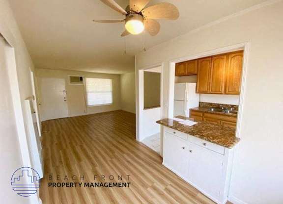 an empty kitchen and living room with a ceiling fan