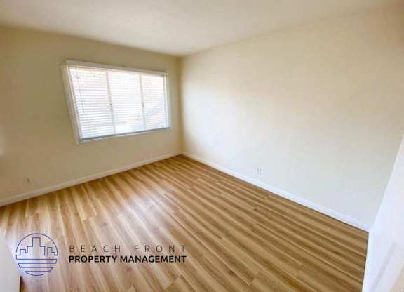 an empty room with wood flooring and a window