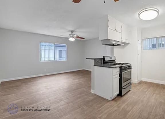 A kitchen with a stove top oven and a fan on the ceiling.