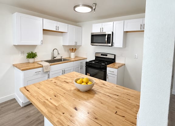 A kitchen with a wooden table and white cabinets.