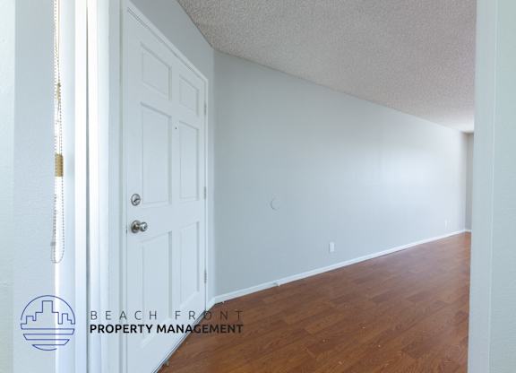 A white door with a wooden floor and a logo that says Beach Front Property Management.