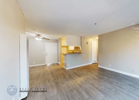 A spacious room with wooden flooring and a white door leading to another room.