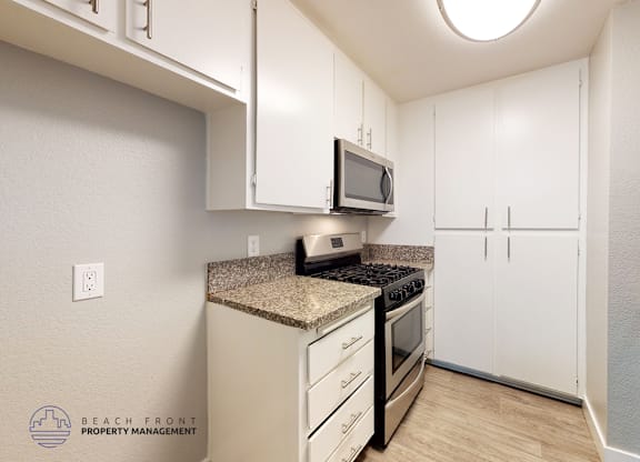 A kitchen with white cabinets and a granite countertop.