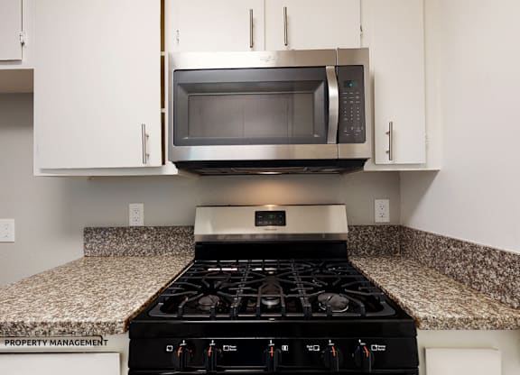 A modern kitchen with a stove and microwave above it.