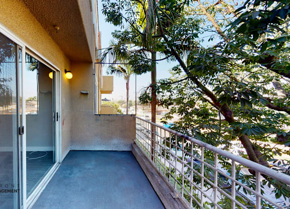 A balcony with a glass door leading to a beach.