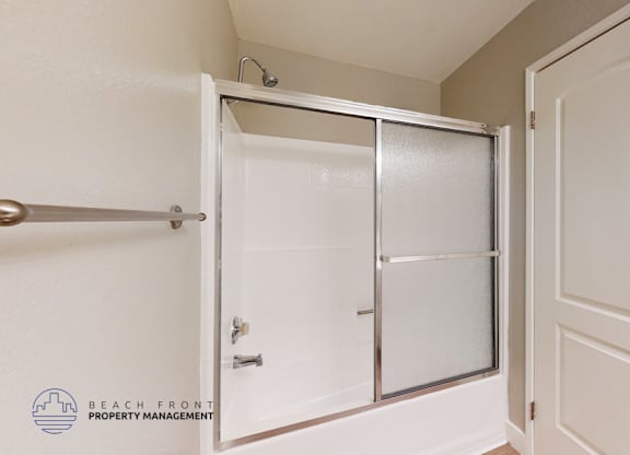 A white door with a glass panel is open to a white hallway.