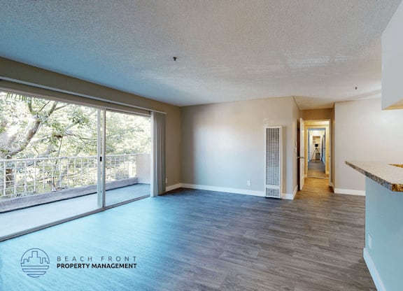 A spacious room with a view of the trees through the sliding glass doors.