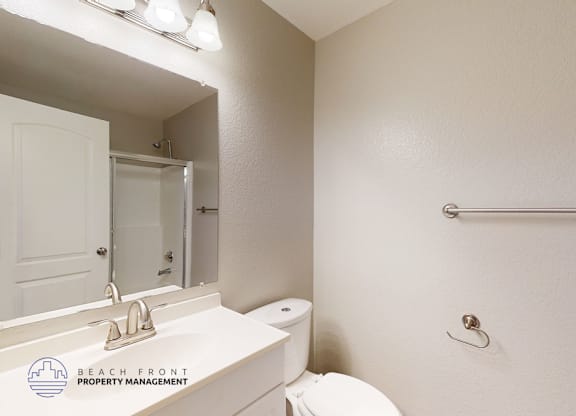 A white bathroom with a toilet, sink, and towel rack.
