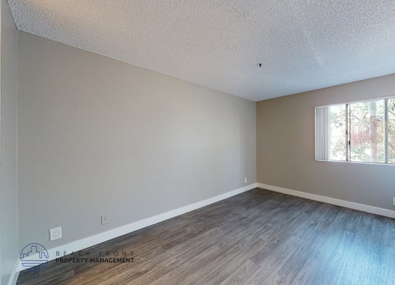 A room with a window and wooden flooring.