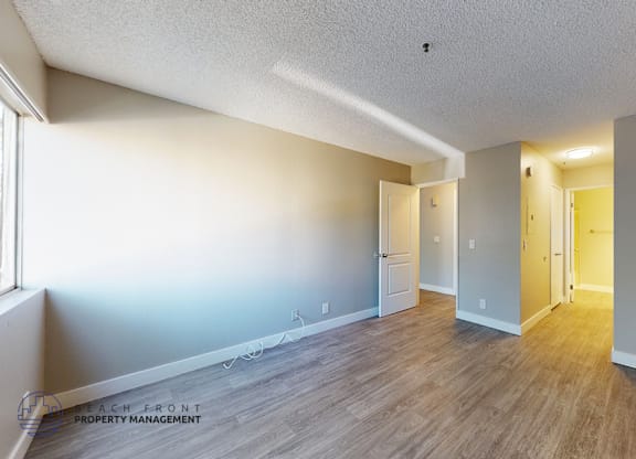 A spacious room with wooden flooring and white walls.