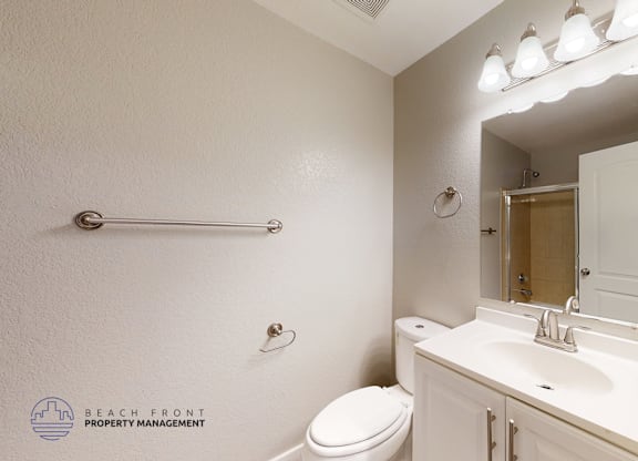 A white bathroom with a toilet, sink, and mirror.