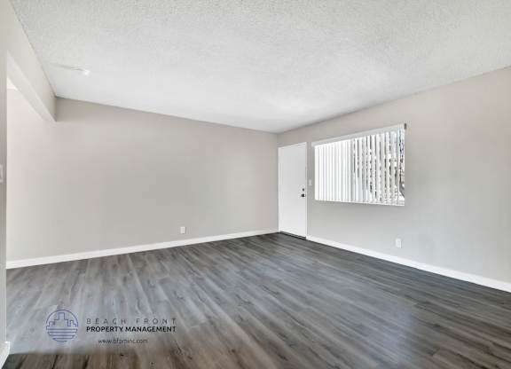 A room with wooden flooring and a window with blinds.