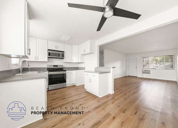 A spacious kitchen with white cabinets and a wooden floor.
