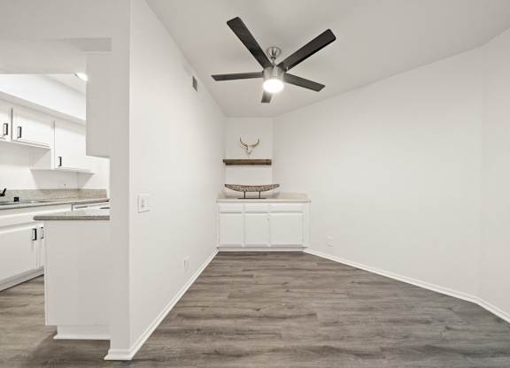 A room with a ceiling fan and a deer head on the wall.